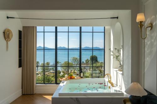 a bathroom with a tub in front of a large window at Mello Hotel in Shenzhen