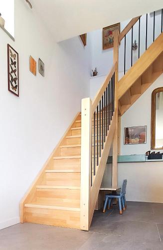a wooden staircase in a home with a blue chair at Le Reflet du Trèfle in Puybegon