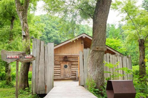 a wooden cabin in the woods with a wooden walkway at LAMP Nojiriko The Sauna by the Lake in Shinano