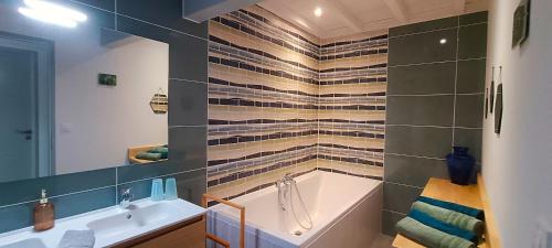a bathroom with a bath tub and a sink at Le Reflet du Trèfle in Puybegon
