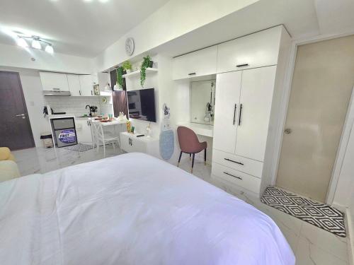 a white bedroom with a bed and a desk at Steff's Condo 722 at Centrio Tower in Cagayan de Oro