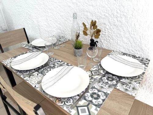 - une table à manger avec des assiettes blanches et des verres dans l'établissement Studio proche du Futuroscope, à Chasseneuil du poitou, à Chasseneuil-du-Poitou