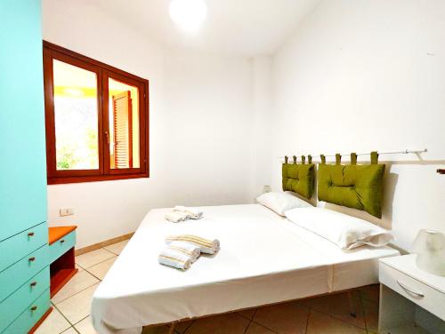 a bedroom with a large white bed with a window at Gamm Simius Home Holiday in Villasimius
