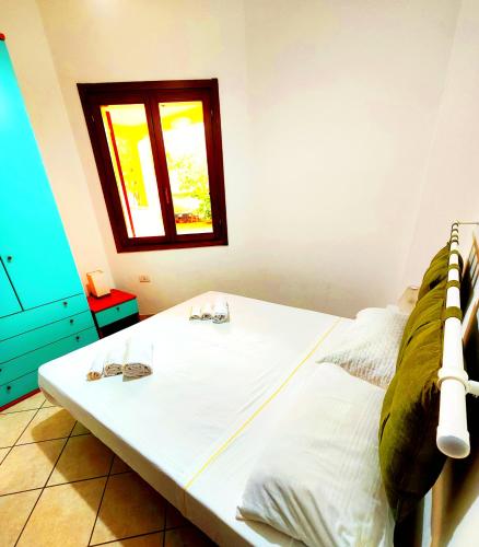 a bedroom with a white bed with a window at Gamm Simius Home Holiday in Villasimius