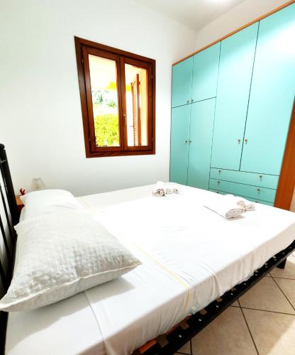 a bedroom with a bed with blue cabinets and a window at Gamm Simius Home Holiday in Villasimius