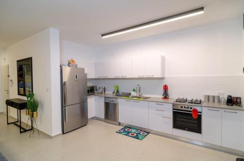a large kitchen with white cabinets and stainless steel appliances at Michaelangelo Luxury Garden Apartment with Private Pool in Tiberias