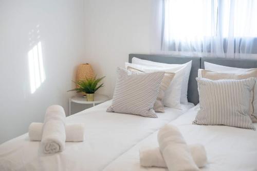 a white bedroom with white pillows and a bed at Michaelangelo Luxury Garden Apartment with Private Pool in Tiberias