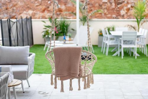 a patio with a swing and chairs and a table at Michaelangelo Luxury Garden Apartment with Private Pool in Tiberias
