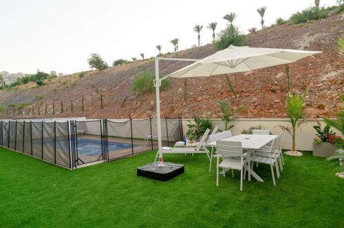 a patio with an umbrella and a table and chairs at Michaelangelo Luxury Garden Apartment with Private Pool in Tiberias