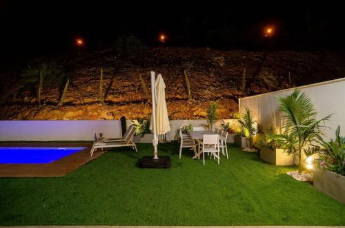 a patio with a table and an umbrella and a pool at Michaelangelo Luxury Garden Apartment with Private Pool in Tiberias