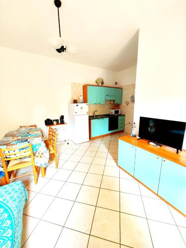a living room with a table and a kitchen at Gamm Simius Home Holiday in Villasimius