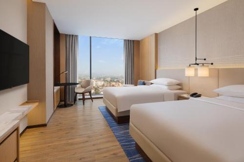 a hotel room with two beds and a tv at Courtyard by Marriott Ranchi in Rānchī
