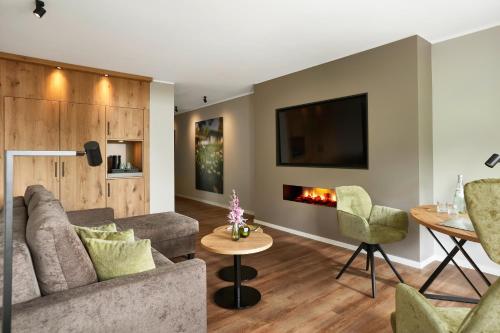 a living room with a couch and chairs and a fireplace at Sporthotel Grafenwald 4 Sterne Superior in Daun