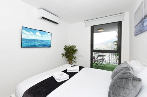 a white bedroom with a large bed and a window at My View 2 bedroom apartment by the lake in Tiberias