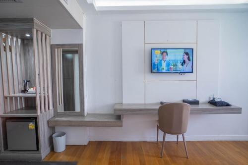 a living room with a chair and a tv on the wall at Thong Tarin Hotel in Surin