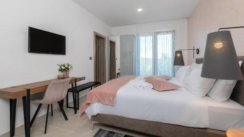 een slaapkamer met een bed, een bureau en een televisie bij Villa Callista by Villas Holiday in Ružići