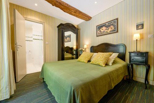 a bedroom with a green bed with yellow pillows at Hôtel Diderot in Chinon
