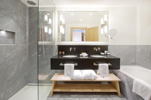 a bathroom with a sink and a tub and a mirror at ANGELA Landhaus Fine Serviced Apartments and Double Rooms in Lech am Arlberg