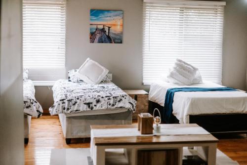 a room with two beds and a table and windows at Cabins Sodwana Bay - antibootika in Sodwana Bay