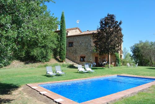 a swimming pool in front of a house with chairs at Masia Can Sisó in Crespiá