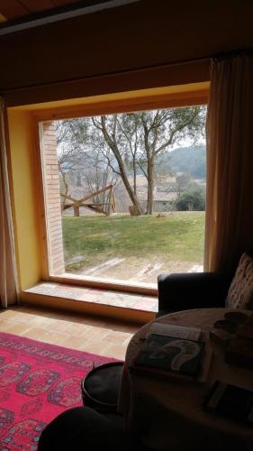 a bedroom with a large window with a view of a field at Masia Can Sisó in Crespiá