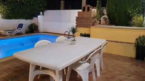 a white table and chairs next to a pool at ADOSADO DE LUJO CON PISCINA PRIVADA en ZONA MUY TRANQUILA in Gandía