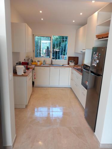 une cuisine avec des armoires blanches et des appareils en acier inoxydable dans l'établissement Havre de paix, mer et jardin luxuriant, à Fréjus