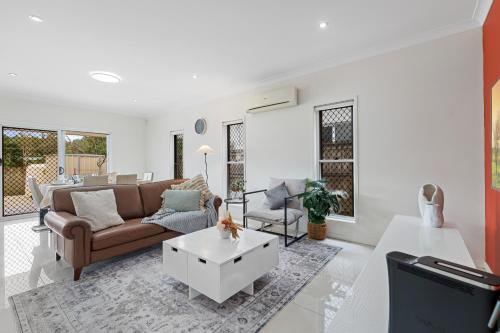 a living room with a couch and a table at Dual Ensuite Coopers Plains Home by QEII, QSAC and Griffith Uni in Brisbane