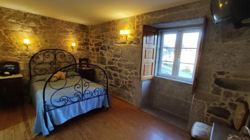 a bedroom with a bed in a room with a window at Casa de Turismo Rural Os Petroglifos in Boiro