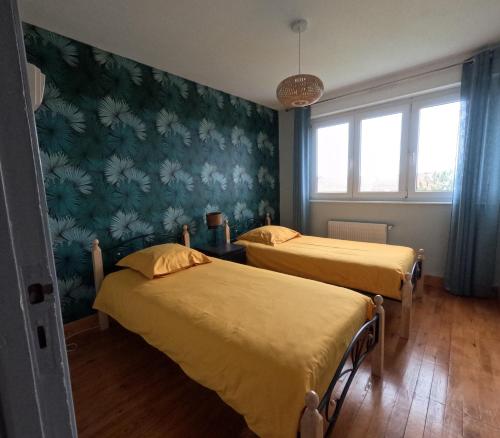 two beds in a room with green wallpaper at Gîte « Les Oyats » à 400 m de la plage in Équihen-Plage