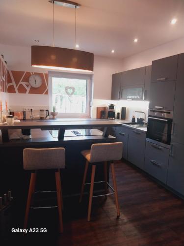 a kitchen with black cabinets and two bar stools at Ferienhaus Seeliebe in Krugsdorf