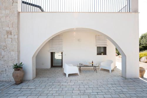 an arched patio with white chairs and a table at Riofavara Winery in Val di Noto in Ispica