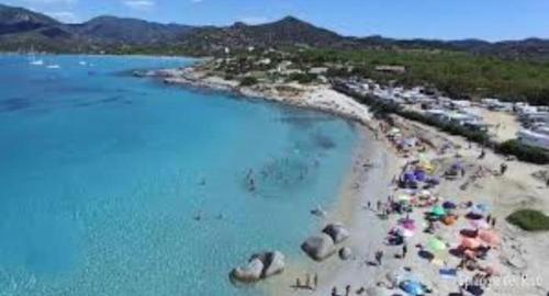 a beach with people and umbrellas in the water at Gamm Simius Home Holiday in Villasimius