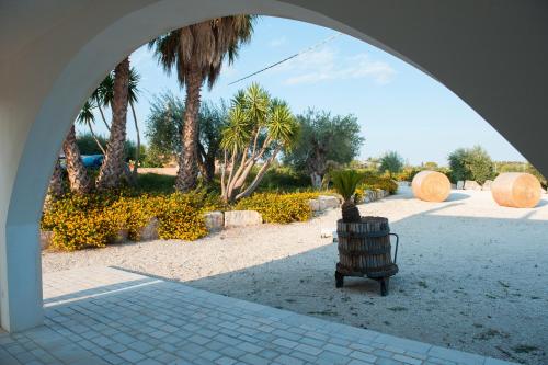 an archway with a bench in a park with palm trees at Riofavara Winery in Val di Noto in Ispica