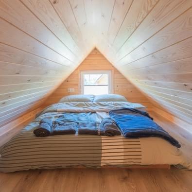 a bed in a tiny house with a window at Mały Karmelowy Domek in Stężyca