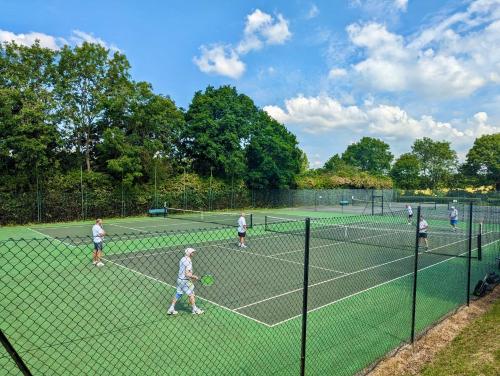 a group of people playing tennis on a tennis court at Birdie Glamping Pod in Great Totham