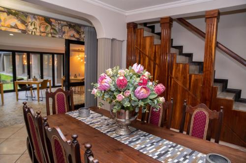 a table with a vase of flowers on it at Iso'Bella Vita Guesthouse in Phalaborwa