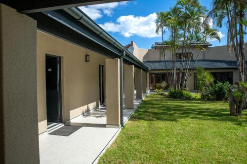 a building with a courtyard with grass and palm trees at Iso'Bella Vita Guesthouse in Phalaborwa