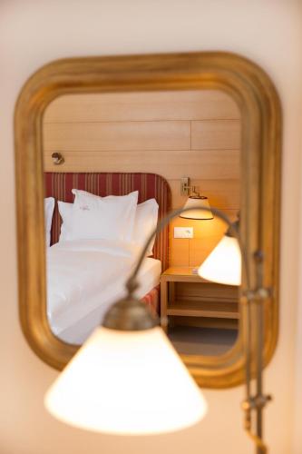 a reflection of a bedroom with a bed in a mirror at ANGELA Landhaus Fine Serviced Apartments and Double Rooms in Lech am Arlberg