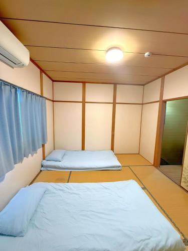 a small room with two beds and a window at 余歓の一戸建てです in Nishi-shibuta