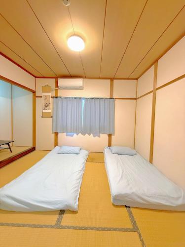 two beds in a room with a window at 余歓の一戸建てです in Nishi-shibuta