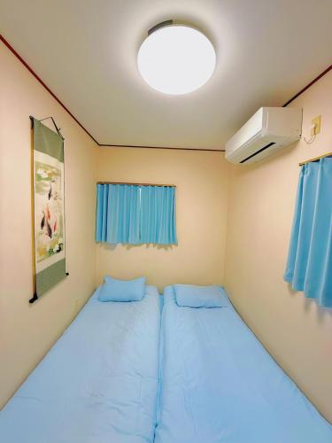 a small room with two beds and a fan at 余歓の一戸建てです in Nishi-shibuta