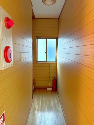a hallway with a window and a red suitcase at 余歓の一戸建てです in Nishi-shibuta