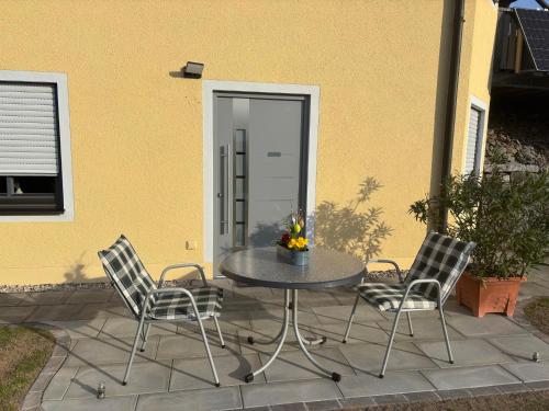 a patio with a table and two chairs and a door at Schwarzachtal Oase in Neunburg vorm Wald