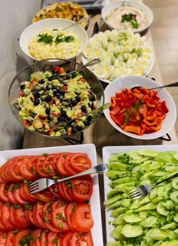 a buffet of food with tomatoes and vegetables on plates at Hotel Basztowy in Sandomierz