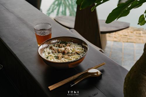 a bowl of food on a table with a glass of beer at TOKI Ecolodge Cao Răm in Hòa Bình