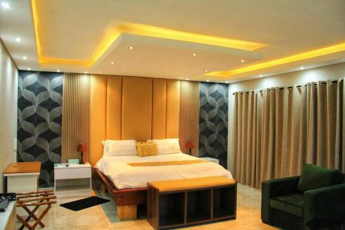 a bedroom with a bed and a couch and a chair at Tlokweng Rose Garden Guesthouse in Gaborone