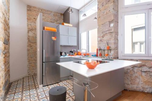 Il comprend une cuisine équipée d'un réfrigérateur en acier inoxydable et de comptoirs blancs. dans l'établissement Appartement cosy plein centre - l'Annexe, à Lyon