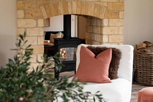 a living room with a fireplace and a couch with a pillow at Willowbrook House- A luxurious countryside retreat set in an idyllic & desirable location close to Soho Farmhouse and lots of Cotswold attractions - Dogs welcome in Kiddington