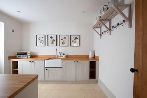 a kitchen with white cabinets and a sink and a chandelier at Willowbrook House- A luxurious countryside retreat set in an idyllic & desirable location close to Soho Farmhouse and lots of Cotswold attractions - Dogs welcome in Kiddington